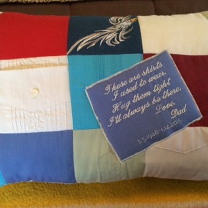 May include: A blue and white patchwork pillow with a white embroidered message that reads "These are shirts I used to wear. Hug them tight I'll always be there. Love, Dad 3.5.1928-1.14.2015".
