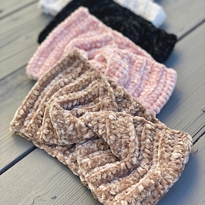 Könnte beinhalten: Eine Sammlung von fünf Stirnbändern mit samtiger Textur, die in einer Reihe angeordnet sind. Die Stirnbänder haben ein gedrehtes Knotendesign in der Mitte und sind in verschiedenen Farben erhältlich, darunter Beige, Hellrosa, Schwarz, Weiß und Hellblau.