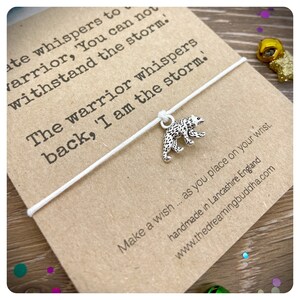 May include: White string bracelet with a silver bear charm. The card attached to the bracelet reads "ate whispers to warrior, 'You can not withstand the storm. The warrior whispers back, 'I am the storm.' Make a wish... as you place on your wrist. handmade in Lancashire England www.thedreamingbuddha.com"