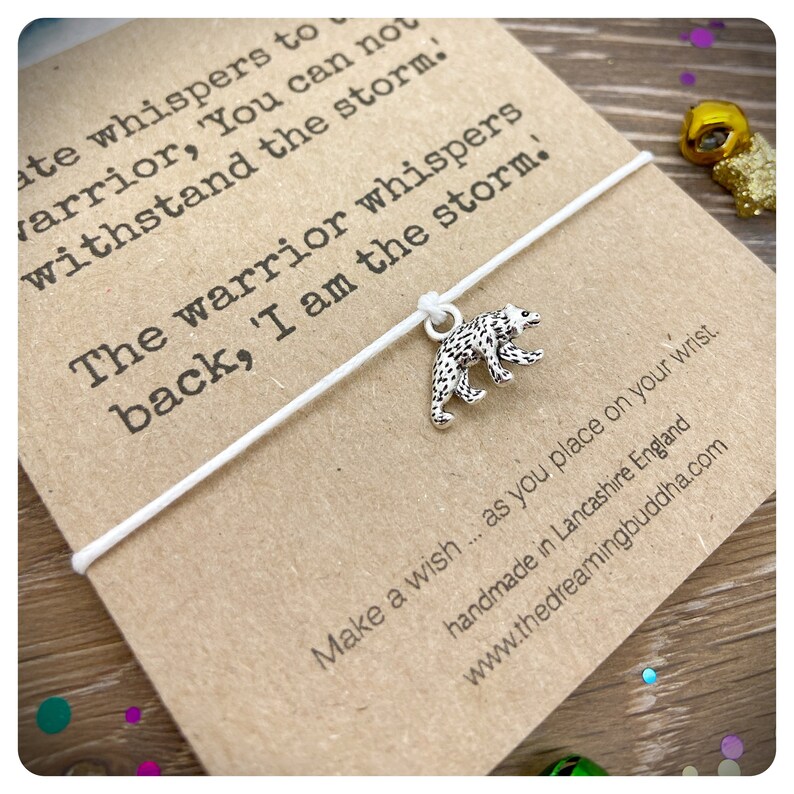 May include: White string bracelet with a silver bear charm. The card attached to the bracelet reads "ate whispers to warrior, 'You can not withstand the storm. The warrior whispers back, 'I am the storm.' Make a wish... as you place on your wrist. handmade in Lancashire England www.thedreamingbuddha.com"