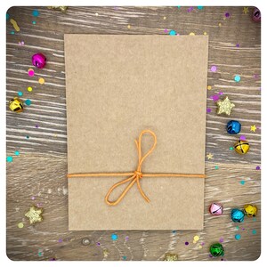 May include: A brown paper card with a knotted orange string tied around it. The card is on a wooden surface with colorful confetti scattered around it.