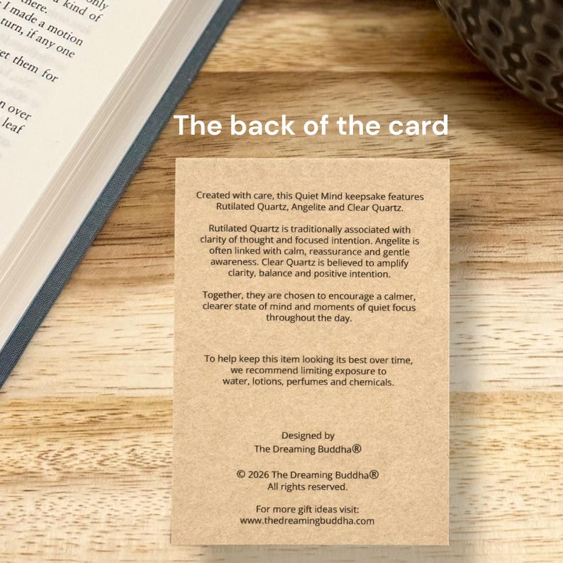 May include: A beige card with text that reads "The back of the card" and detailed information about Rutilated Quartz, Angelite, and Clear Quartz. The card is designed by The Dreaming Buddha.