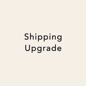 May include: The words "Shipping Upgrade" are displayed in a black, sans-serif font against a cream-colored background. The text is centered and takes up a significant portion of the image.