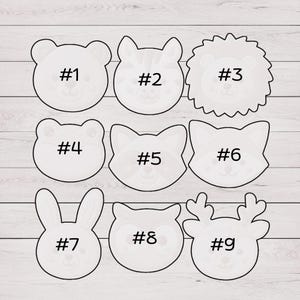 May include: Nine white animal-shaped cookie cutters. The shapes include a bear, tiger, lion, bear, fox, fox, bunny, owl, and reindeer. Each cutter is labeled with a number from #1 to #9.