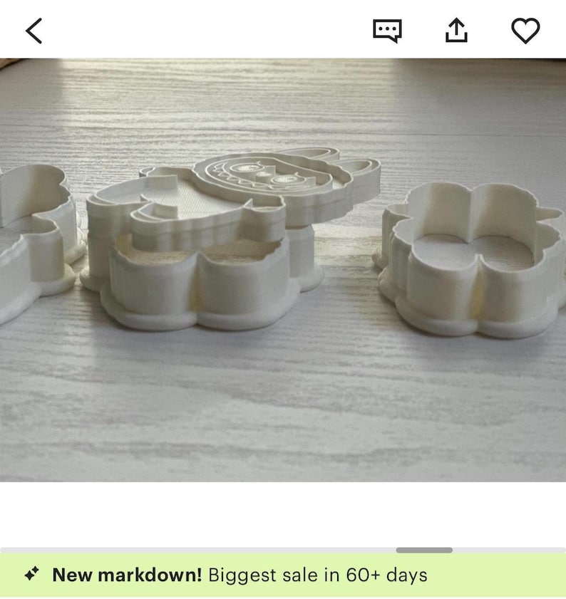 Puede incluir: Cortadores de galletas de pl&aacute;stico blanco con forma de oso, flor y otra forma. El cortador de oso tiene rasgos faciales detallados. Los cortadores est&aacute;n sobre una superficie de madera de color claro.