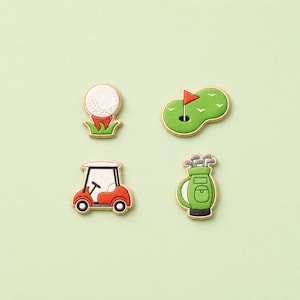 May include: Four golf-themed cookies decorated with icing. The set includes a white golf ball on a red tee, a green putting green with a red flag, a red and white golf cart, and a green golf bag filled with various golf clubs and accessories.