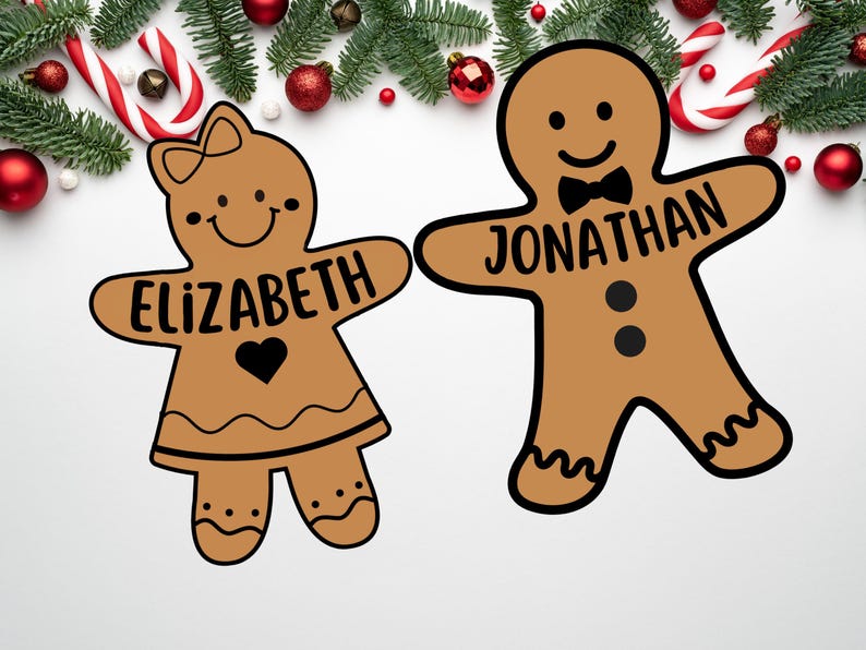 Peut inclure: Deux personnages en pain d'&eacute;pices, l'un avec le nom "Elizabeth" et l'autre avec le nom "Jonathan", sont d&eacute;cor&eacute;s de gla&ccedil;age noir et entour&eacute;s de d&eacute;corations de No&euml;l.