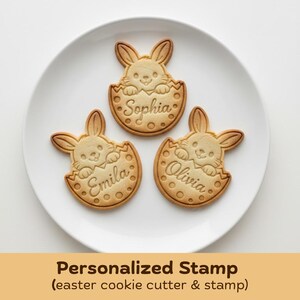 May include: Three Easter bunny-shaped cookies on a white plate. Each cookie is light brown and features a bunny emerging from an egg, with names "Sophia", "Emila", and "Olivia" inscribed. The image includes the text "Personalized Stamp (easter cookie cutter & stamp)".