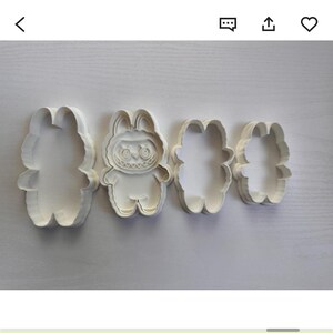 Puede incluir: Cuatro cortadores de galletas blancos con forma de conejo. Uno tiene una cara detallada y siniestra. Los otros tres son contornos simples. La imagen est&aacute; tomada desde arriba, sobre una superficie clara.