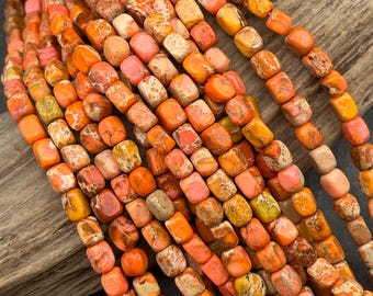 May include: A collection of multiple strands of square-shaped beads in shades of orange, coral, and yellow. Each bead features a unique marbled texture with natural veining patterns, creating a vibrant and varied appearance across the entire set.