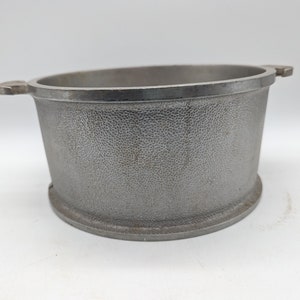 Puede incluir: Un molde para hornear de aluminio plateado con dos asas. El molde tiene una superficie texturizada.