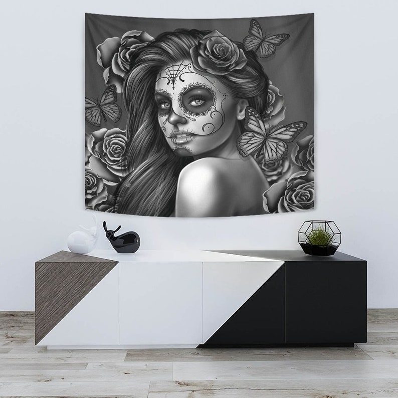 May include: Black and white tapestry featuring a woman with a sugar skull makeup design, surrounded by roses and butterflies.