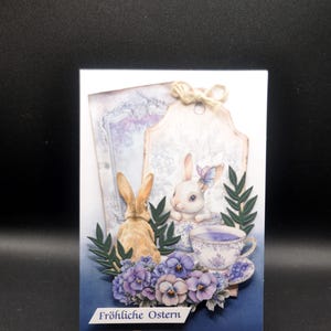handgemachte Osterkarte mit Porzellantasse und Hase, blaue Stiefmütterchen zum Osterbrunch, nostalgische Feiertage mit Kaninchen und Gold