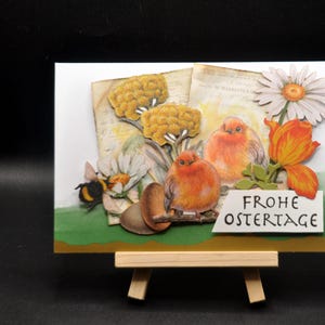Osterkarte mit Goldkante, orange Vögel zwischen Frühjahrsblüher und Eiern, Umschlag mit gleichen Farbverlauf wie Karte, Hummel auf Margerite