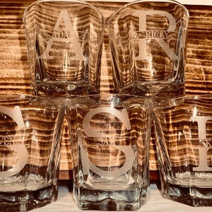 May include: Six clear glass tumblers with a frosted design. Each tumbler has a different letter etched on the front, with a name underneath. The names are "Adam", "Ricky", "Steven", "Sam", "Kaden", and "Lily".