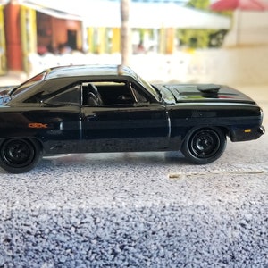 May include: A black 1969 Plymouth Road Runner with a rear spoiler and "GTX" lettering on the side. The car is a toy model.