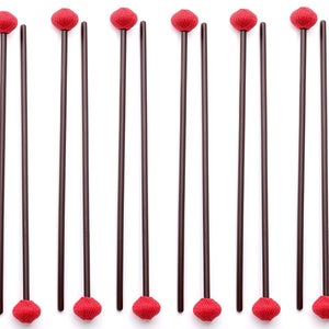 Può includere: Un set di 16 mazze rosse e marroni con teste rotonde e morbide. Le mazze sono disposte in due file da otto, con le teste rivolte verso lo spettatore.