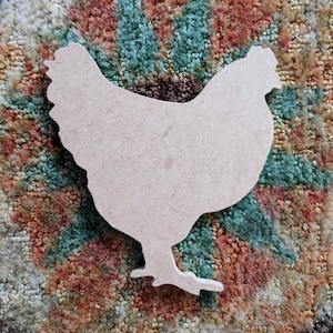 May include: A wooden cutout of a chicken in a light brown color. The cutout is on a colorful patterned rug.