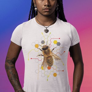 Puede incluir: Camiseta blanca con una ilustración de abeja y un diseño de panal. La abeja es marrón y amarilla, sobre un patrón geométrico en amarillo, gris y naranja. La camiseta es de manga corta.