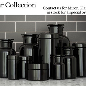 May include: A collection of black glass jars with lids, some with labels, arranged on a gray tiled surface.  Contact us for Miron Glass not in stock for a special order.