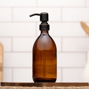 May include: A brown glass bottle with a black pump dispenser. The bottle is sitting on a wooden surface.