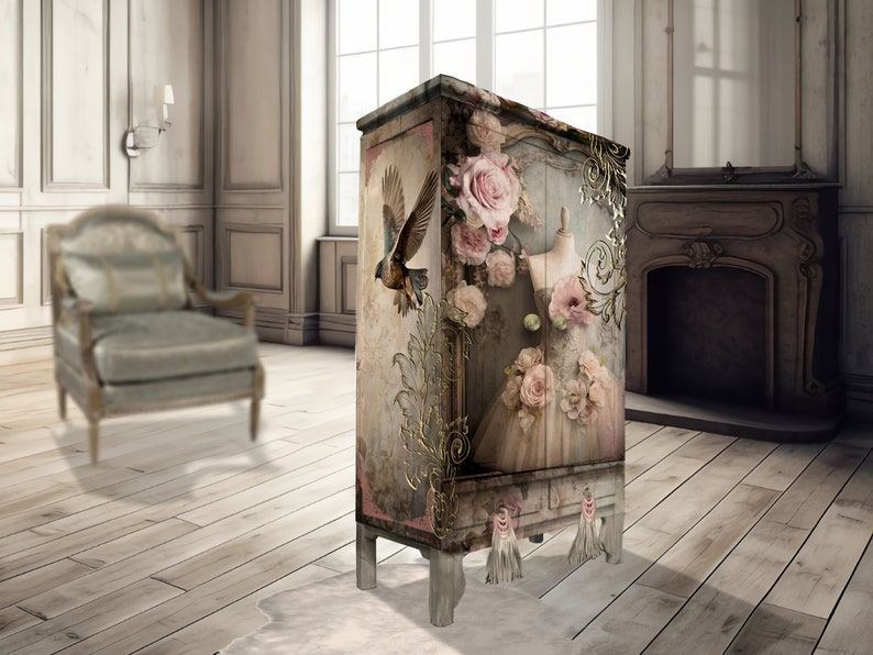 May include: A vintage-style cabinet with a distressed white finish. The cabinet is decorated with a floral design featuring pink roses, a bird, and a gold-leaf accent. The cabinet has a single drawer and two doors.