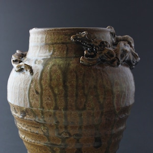 Könnte beinhalten: Eine braune Keramikvase mit einer strukturierten Oberfläche und einem einzigartigen Design. Die Vase hat eine breite Öffnung und einen schmalen Boden. Sie ist mit einer braunen Glasur verziert und hat einen Tropf-Glasureffekt.