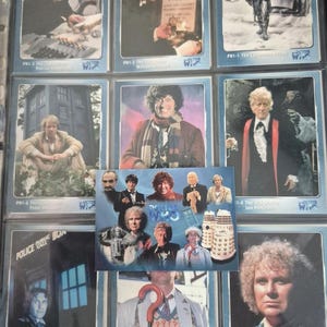 May include: A collection of Doctor Who trading cards featuring various actors who played the Doctor. The cards showcase images of the Doctor in different costumes and settings, with the Doctor Who logo visible.