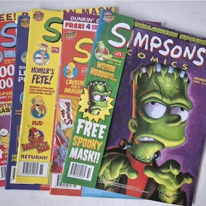 Puede incluir: Varios cómics de Los Simpson, con diferentes portadas con personajes como Homer y Bart Simpson. Los cómics tienen colores vibrantes y texto como "Halloween Special" y "Free Spooky Mask!!".