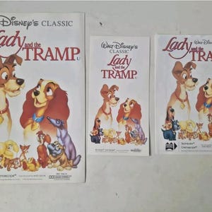 May include: Three vintage movie posters for the Disney classic film Lady and the Tramp. The posters are white with red and black text and feature a cartoon image of Lady and Tramp.