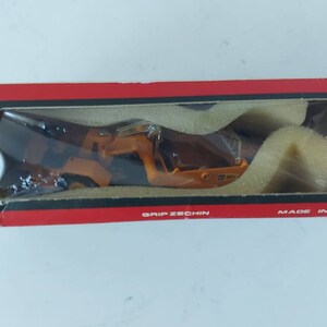 以下が含まれることがあります： 赤い箱に黄色いおもちゃの建設車両が入っています。箱には「GRIP ZECCHIN」と「MADE IN JAPAN」の文字が書かれています。