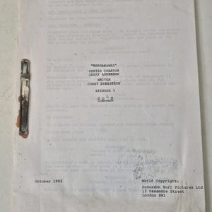 Puede incluir: Un guion de rodaje vintage de la serie de televisión "Terrahawks", fechado en octubre de 1982. El documento incluye el título del episodio "Gold" y los nombres del creador de la serie, Gerry Anderson, y del escritor Cubby Dreistein. Un clip metálico sujeta el guion.