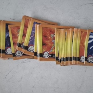 May include: A collection of vintage Pokémon trading cards. The cards feature various Pokémon characters, including Bulbasaur, Mewtwo, and others. Each card has a unique number and a colorful illustration. The cards are stacked and fanned out, showing their fronts.