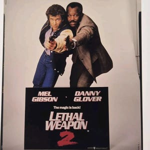 Può includere: Un poster del film "Lethal Weapon 2" con Mel Gibson e Danny Glover che imbracciano pistole. Il poster ha uno sfondo nero con il titolo del film in bianco e rosso. È visibile anche lo slogan "The magic is back!"