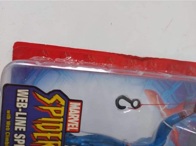 K&ouml;nnte beinhalten: Eine blaue und rote Marvel Spider-Man Actionfigur mit einer Web-Line-Funktion. Die Figur ist in einer durchsichtigen Plastik-Blisterverpackung mit einer roten Kopfkarte verpackt, auf der "MARVEL" und "WEB-LINE SPIDER-MAN" mit dem Text "with Web Climbing Action" steht.