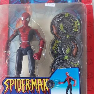 Pode incluir: Uma figura de a&ccedil;&atilde;o do Homem-Aranha vermelha e azul com uma tampa de esgoto na m&atilde;o. A figura &eacute; embalada com tr&ecirc;s tampas de esgoto que t&ecirc;m limo verde nelas. A embalagem diz "Street Fighting Spider-Man with Sewer Cap Hurling Action!"
