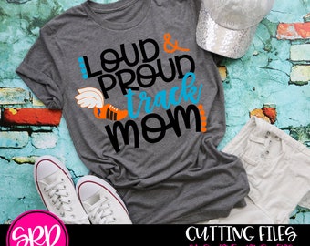 May include: Gray t-shirt with the text "Loud & Proud Track Mom" in black and orange. A blue and orange running shoe with wings is above the text. The shirt is on a blue and orange brick background.
