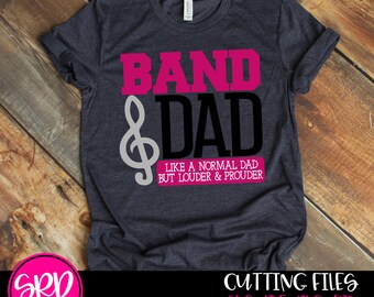 May include: A dark gray t-shirt with the text "BAND & DAD" in black and pink. The text "LIKE A NORMAL DAD BUT LOUDER & PROUDER" is in a white rectangle below the main text. A treble clef is to the left of the text "DAD".