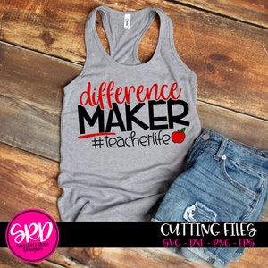 May include: A gray tank top with the text "difference MAKER #teacherlife" in black and red. A red apple graphic is next to the text. The tank top is on a wooden surface.