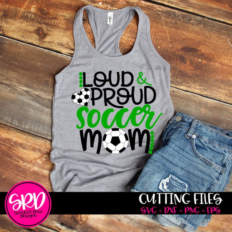 May include: A gray tank top with the text "Loud & Proud Soccer Mom" in black and green lettering. A soccer ball is in the center of the text. The tank top is on a wooden surface.