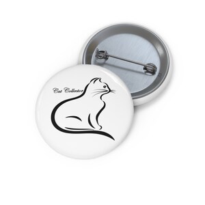 May include: White button pin with a black outline of a cat and the words "Cat Collector" in a script font. The pin is round and has a metal backing with a pin. The cat is sitting and looking to the right.