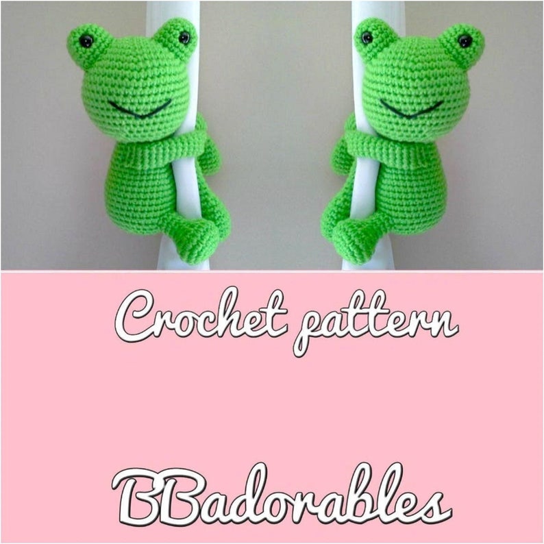May include: Crochet pattern for two green frog amigurumi toys. The frogs are holding onto a white pole and have black eyes. The text "Crochet pattern" and "Badorables" is written in white on a pink background.