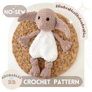 May include: A crocheted doll with large ears, a white tunic, and brown limbs. The doll is made with a soft, textured yarn. The image includes the text "NO-SEW" and "CROCHET PATTERN". The doll is set against a woven background.