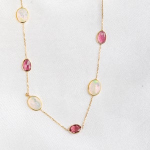 May include: A gold chain necklace with alternating oval-shaped white opal and pink tourmaline gemstones.
