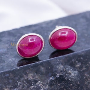 Może przedstawiać: Para srebrnych kolczyków z owalnymi różowymi kamieniami szlachetnymi.