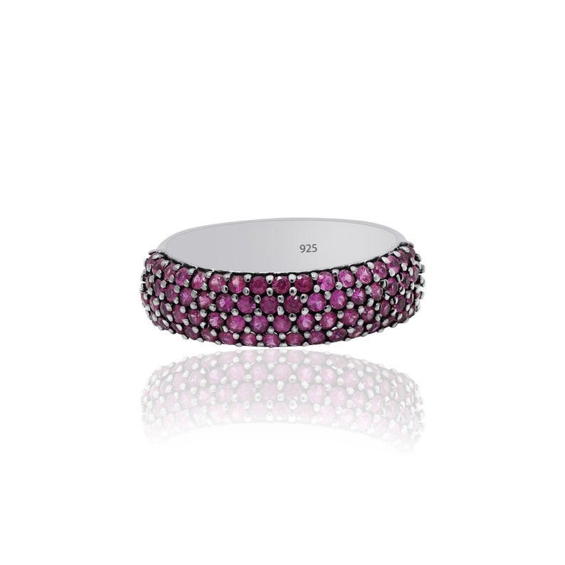 May include: A silver band ring with a row of pink gemstones. The ring is marked with the number 925.