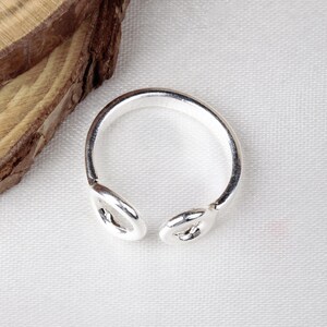 Op de afbeelding: Een zilveren ring met een uniek ontwerp met twee verbonden cirkels. De ring is simpel en elegant.