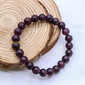 May include: A purple gemstone bracelet with round beads. The bracelet is made of natural stones and is a beautiful accessory for any occasion.