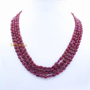 May include: A multi-strand necklace made of oval-shaped ruby beads. The necklace is made of four strands of beads and is approximately 18 inches long.