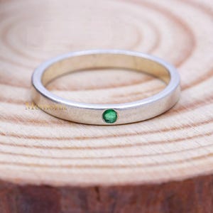 Op de afbeelding: Een eenvoudige zilveren ring met een kleine groene edelsteen in het midden.